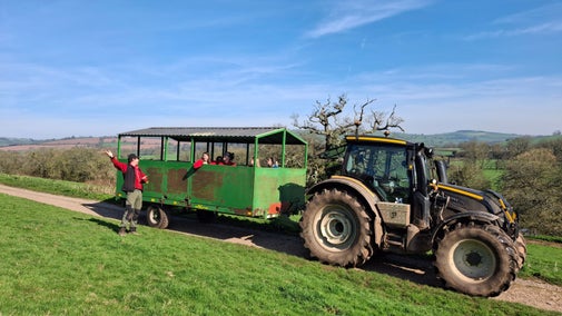 A tractor pulling a trailer with seats for passengers on the Killerton estate